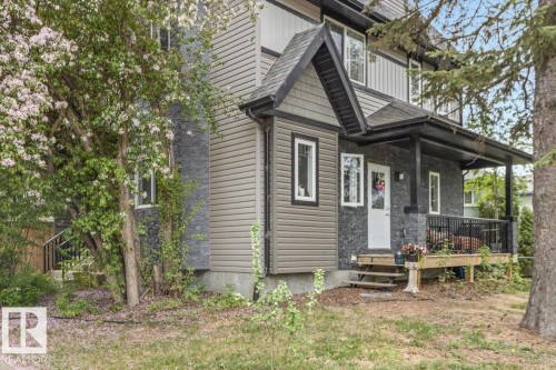 Exterior featuring multi-toned siding, dark gray stone accents, and a covered front porch with black railings - 3 7210 96 Street, Edmonton, AB - Outdoor With Deck Patio Veranda