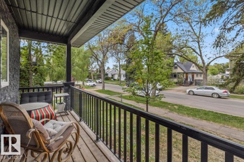 Covered front porch featuring black railing, wood-finish decking, and stone-look siding - 3 7210 96 Street, Edmonton, AB - Outdoor