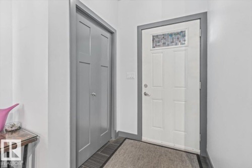 Entryway featuring a white paneled door with decorative glass transom, dark grey trim, and dark wood-finish flooring - 3 7210 96 Street, Edmonton, AB - Indoor Photo Showing Other Room