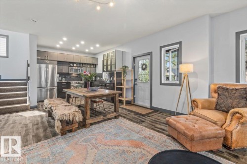 Open-concept living space featuring wood-finish flooring, a contemporary kitchen with stainless steel appliances, dark cabinetry, and recessed lighting - 3 7210 96 Street, Edmonton, AB - Indoor Photo Showing Living Room