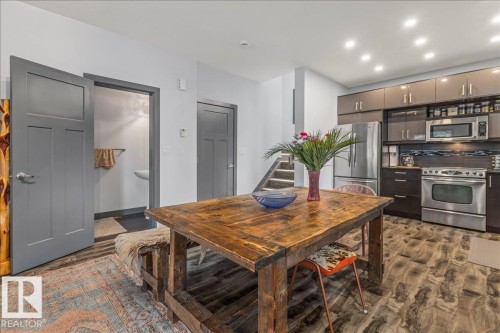 Open-concept kitchen and dining area featuring wood-finish flooring, stainless steel appliances, modern cabinetry with varied finishes, a built-in microwave, and recessed lighting - 3 7210 96 Street, Edmonton, AB - Indoor Photo Showing Kitchen