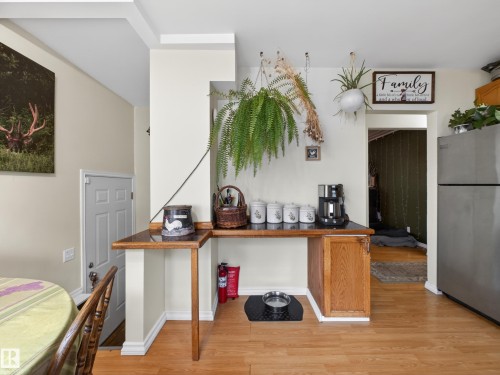 Kitchenette with a wood-finish countertop, stainless steel refrigerator, and wood-finish flooring - 10809 150 Street, Edmonton, AB 