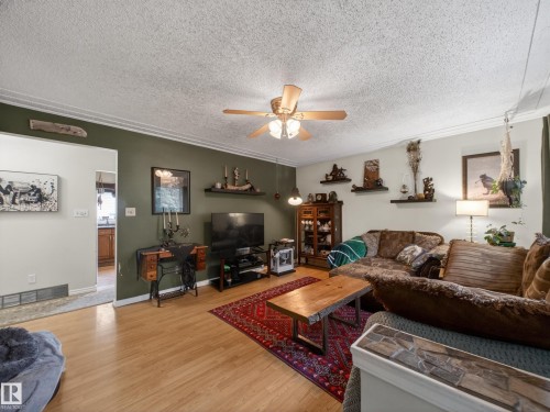 Living area featuring wood-finish flooring, a ceiling fan with integrated lighting, and crown molding - 10809 150 Street, Edmonton, AB 