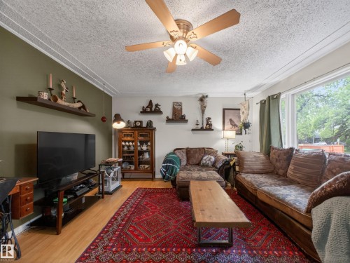 Living room featuring wood-finish flooring, a large picture window, and a ceiling fan with integrated lighting - 10809 150 Street, Edmonton, AB 