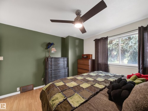 Room featuring wood-finish flooring, a ceiling fan, and a window with white trim - 10809 150 Street, Edmonton, AB 