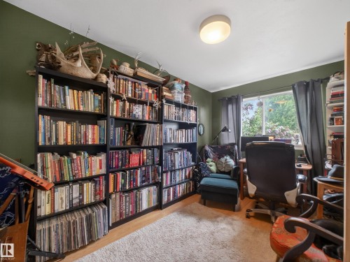 Dedicated room featuring extensive built-in shelving, a large window with exterior greenery, hard-surface flooring, and a flush-mount ceiling light - 10809 150 Street, Edmonton, AB 