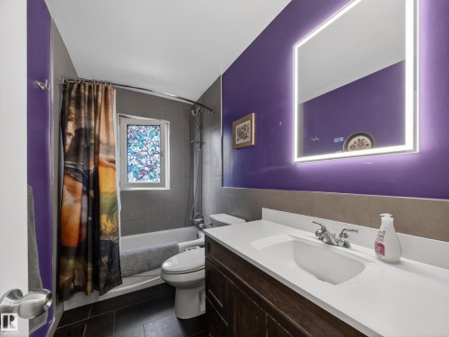 Bathroom featuring a dark wood-finish vanity with an integrated white sink and a lighted mirror - 10809 150 Street, Edmonton, AB 
