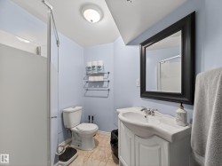 Bathroom featuring a framed mirror, white vanity with integrated sink, toilet, and a shower with a frosted glass panel - 