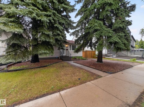 Front exterior featuring a light-colored siding, a dark roof, and a wooden privacy fence - 10809 150 Street, Edmonton, AB 