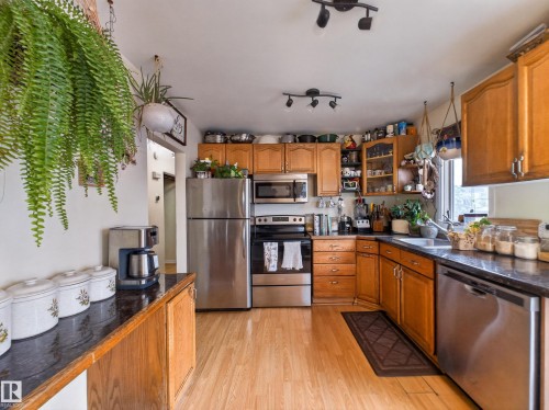 Kitchen featuring wood-finish flooring, dark countertops, and light-toned cabinetry - 10809 150 Street, Edmonton, AB 