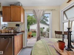 Kitchen area featuring wood cabinetry, dark countertops, and a stainless steel dishwasher - 