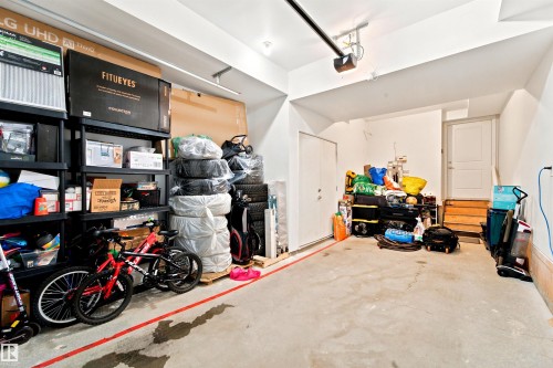 Spacious garage featuring a concrete floor, bright white walls, and an overhead garage door opener - 64 655 Watt Boulevard, Edmonton, AB 