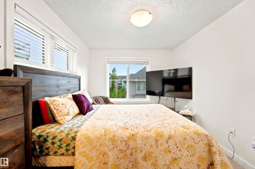 Bedroom with white walls, wood-finish headboard, and two windows featuring blinds - 64 655 Watt Boulevard, Edmonton, AB 