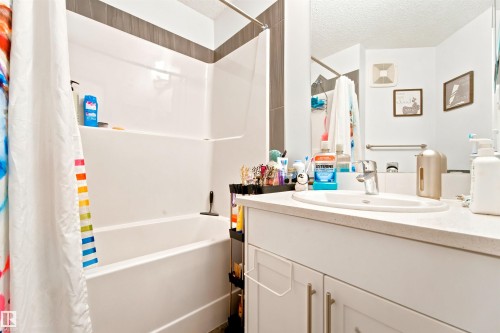 Bathroom featuring a white vanity with an undermount sink, a light-toned countertop, and white cabinetry - 64 655 Watt Boulevard, Edmonton, AB 