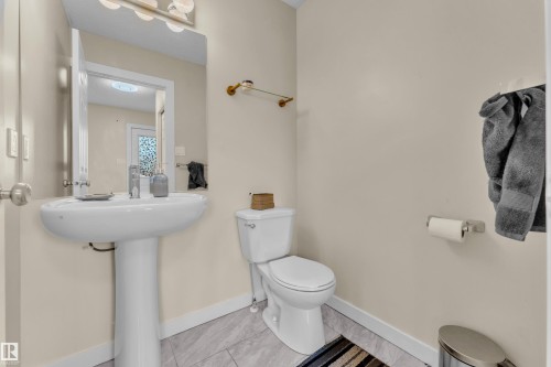Pedestal sink with a polished chrome faucet, rectangular mirror, and overhead vanity lighting - 2362 29A Avenue, Edmonton, AB 