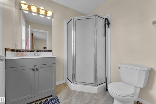 Bathroom featuring a corner shower enclosure with frosted glass, a grey vanity with a white countertop, and mosaic tile backsplash - 2362 29A Avenue, Edmonton, AB 