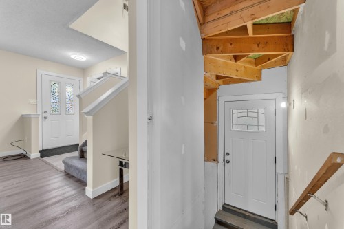 Entryway featuring a white door with decorative glass inserts, wood-finish flooring, and a carpeted staircase with white trim - 2362 29A Avenue, Edmonton, AB 