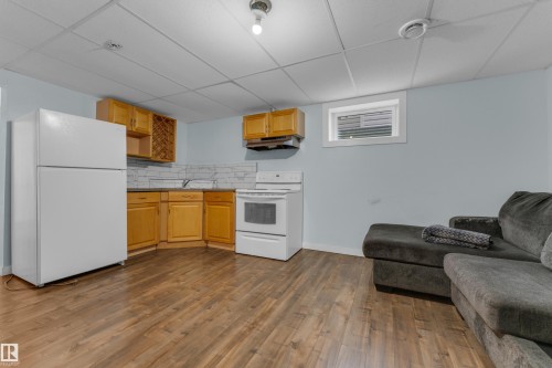 Kitchenette featuring wood cabinetry, white appliances, and a tiled backsplash - 2362 29A Avenue, Edmonton, AB 