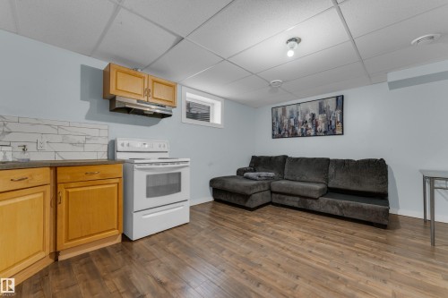 Integrated kitchen area featuring wood-finish cabinetry, white subway tile backsplash, and a white electric range - 2362 29A Avenue, Edmonton, AB 