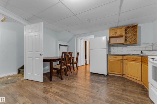 Open-concept living space featuring wood-finish flooring, light wood cabinetry, and a white subway tile backsplash - 2362 29A Avenue, Edmonton, AB 