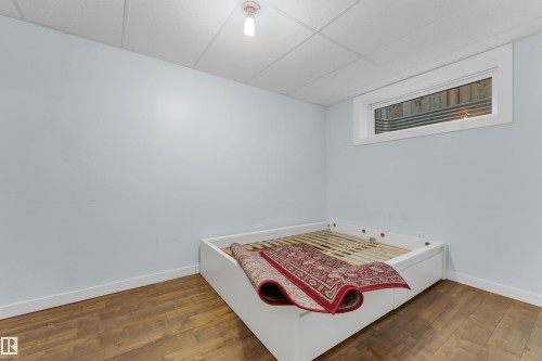 Bedroom featuring wood-finish flooring, light blue walls, and a white drop ceiling - 2362 29A Avenue, Edmonton, AB 
