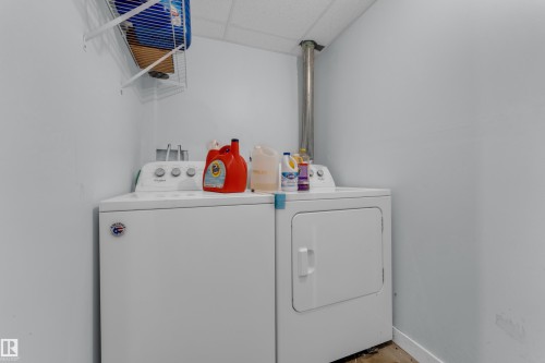 Dedicated laundry area featuring a washer and dryer unit, light-toned walls, and a wall-mounted wire shelf - 2362 29A Avenue, Edmonton, AB 