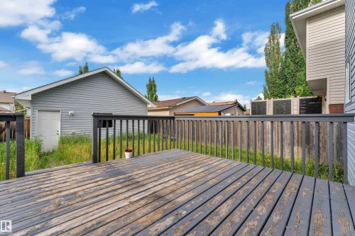 Outdoor wood deck with dark railing and a detached garage featuring light gray siding - 2362 29A Avenue, Edmonton, AB 
