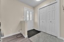 Entryway featuring a white door with decorative glass inserts, bi-fold closet doors, and mixed flooring with wood-finish planks and grey tile - 2362 29A Avenue, Edmonton, AB 
