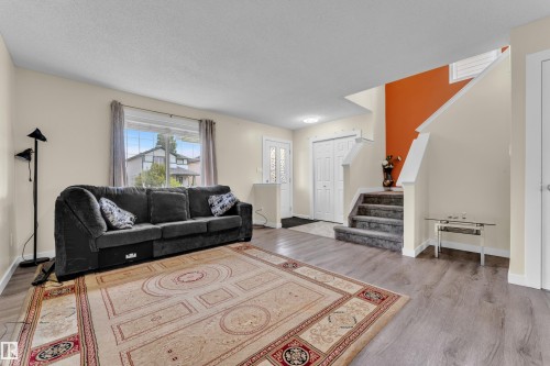 Living area featuring light beige walls and wood-finish flooring - 2362 29A Avenue, Edmonton, AB 