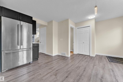 Spacious area featuring wood-finish flooring, light-toned walls, and a contemporary pendant light fixture - 2362 29A Avenue, Edmonton, AB 