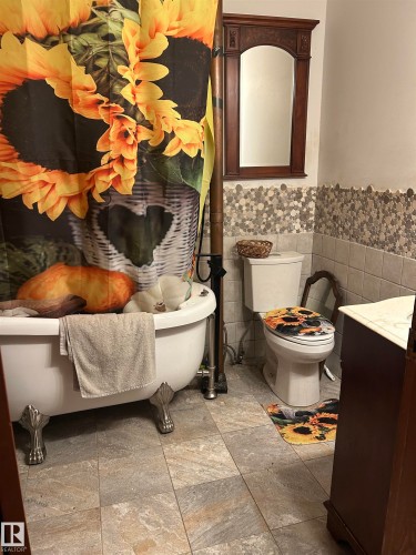 Charming bathroom featuring a classic clawfoot soaking tub with chrome fixtures, ceramic pedestal sink, and low-profile toilet - 5023 50 Street, Vilna, AB - Indoor Photo Showing Bathroom