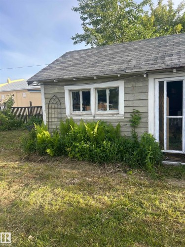 Exterior structure featuring horizontal siding, a shingled roof, two window openings, and a doorway - 5023 50 Street, Vilna, AB - Outdoor