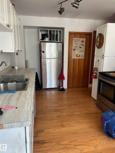 Kitchen featuring light wood-finish flooring, white cabinetry with silver-tone hardware, and a stainless steel refrigerator - 5023 50 Street, Vilna, AB - Indoor Photo Showing Kitchen