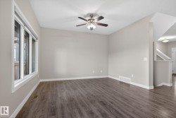 Spacious room featuring wood-finish flooring, a contemporary ceiling fan, and large windows providing ample natural light - 