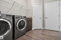 Utility room featuring wood-finish flooring, wire shelving, and a built-in cabinet with a stone-finish countertop - 