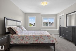 Carpeted bedroom featuring two windows with white trim, a built-in window bench, a flush-mount ceiling light, and light gray wall paint - 