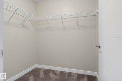 Walk-in closet featuring wire shelving, neutral wall paint, white baseboards, and brown patterned carpeting - 