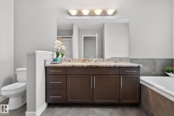 Bathroom featuring a dark wood-finish vanity with a light granite countertop, a large mirror, and overhead lighting - 