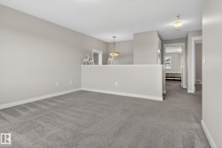 Open loft area with neutral-toned walls and gray carpeting - 