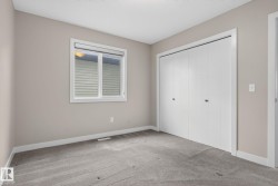 Neutral-toned room featuring a double-pane window with blinds, bi-fold closet doors, light gray carpet flooring, and white trim - 