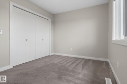 Light gray wall paint with white trim, gray carpet flooring, a window with white casing, and a bi-fold closet - 