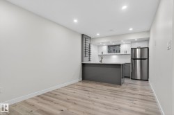 Compact kitchen area featuring a stainless steel refrigerator, white cabinetry, and a light-toned countertop - 