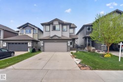 Two-story residence featuring light gray siding with dark gray trim accents and stone veneer detailing - 