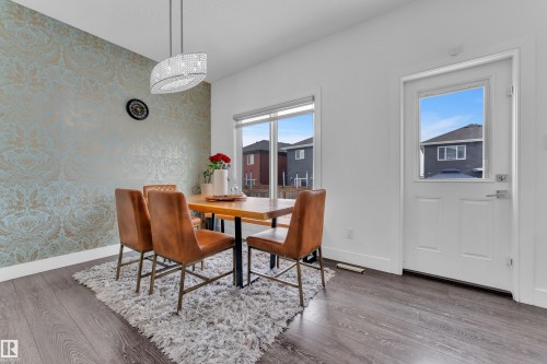 Dining area featuring wood-finish flooring, a decorative accent wall, and a contemporary chandelier - 2630 16A Avenue, Edmonton, AB 