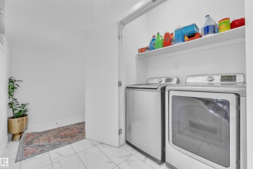 Dedicated laundry area featuring white wall shelving, light-toned tile flooring, and a white door frame - 2630 16A Avenue, Edmonton, AB 
