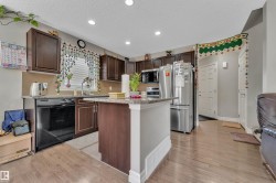 Kitchen featuring wood-finish flooring, dark wood cabinetry, and stainless steel appliances - 