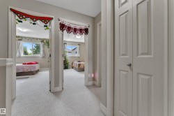Corridor featuring neutral-toned walls, light-colored patterned carpeting, and white trim - 