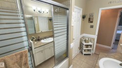 Bathroom featuring a shower with sliding glass doors, a vanity with a drop-in sink and light-toned countertop, and a mirrored medicine cabinet - 
