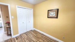 Room featuring wood-finish flooring, white baseboards, and a bi-fold closet with panel doors - 