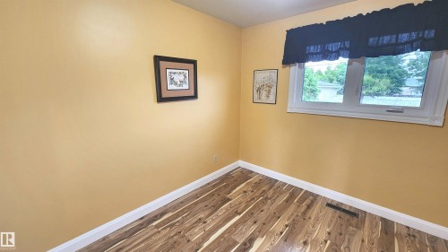 Interior room featuring wood-finish flooring, white baseboards, and light yellow walls - 13307 Delwood Road, Edmonton, AB 